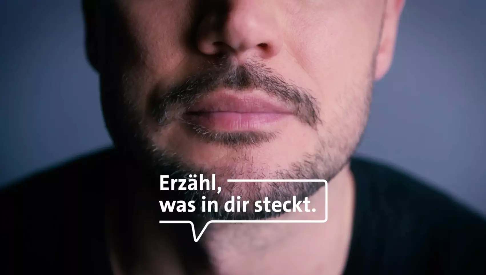 Ein Mann in Nahaufnahme darauf der Text "Erzähl, was in dir steckt."