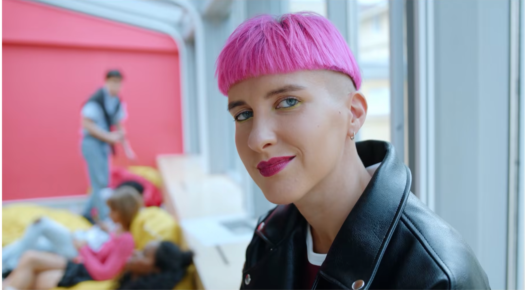 Eine Frau mit pink gefärbten Haaren schaut in die Kamera.